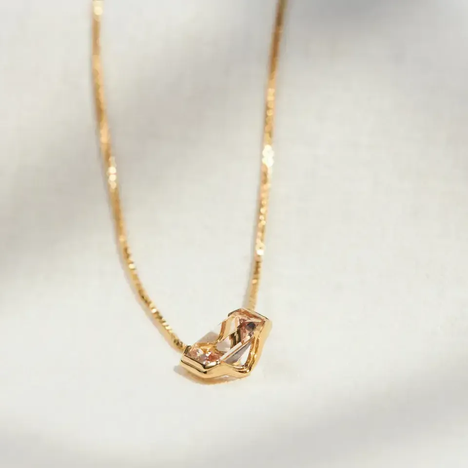 Natural morganite set in an 18K gold vermeil Octagonal pendant, resting on cream linen